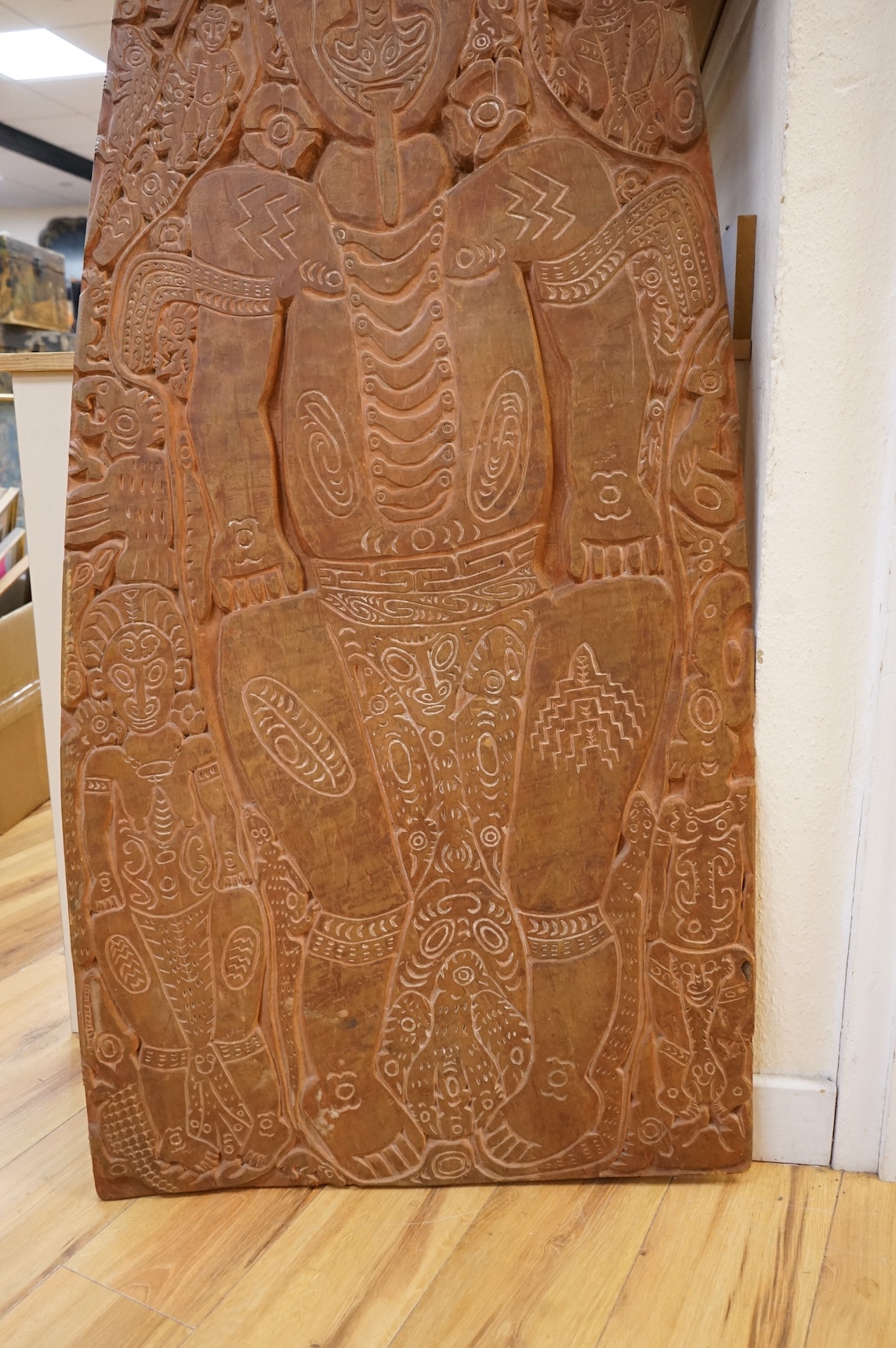 A Papua New Guinea Sepik River large wooden storyboard, relief carved and incised with a central figure surrounded by various animals and spirits, with traces of white pigment, 152cm high
